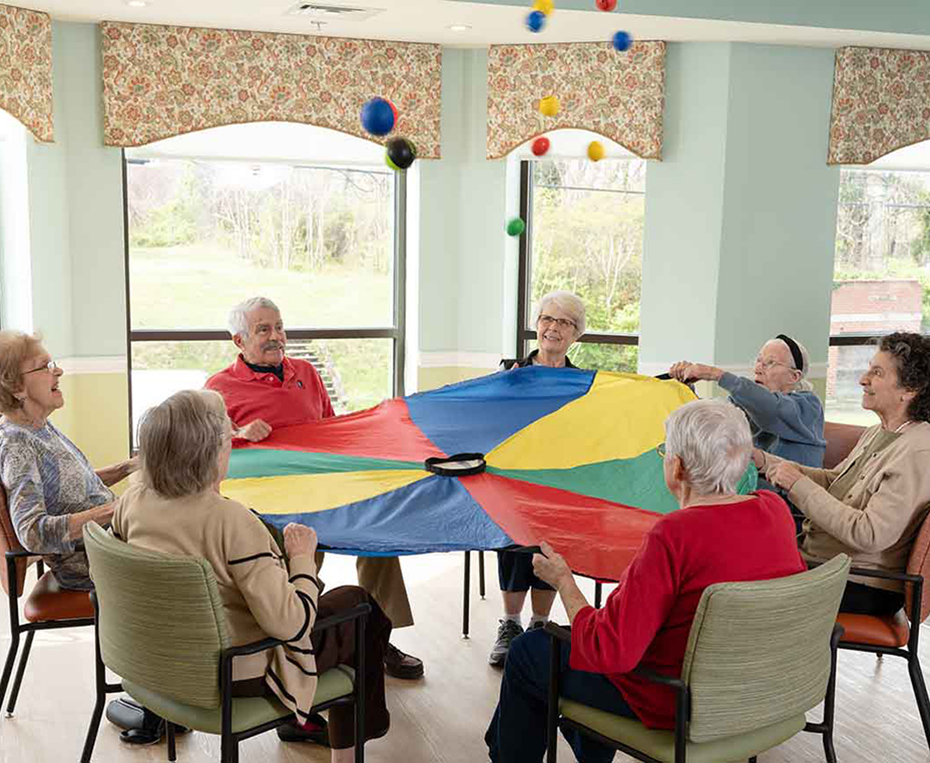 residents playing a game with a colorful parachute